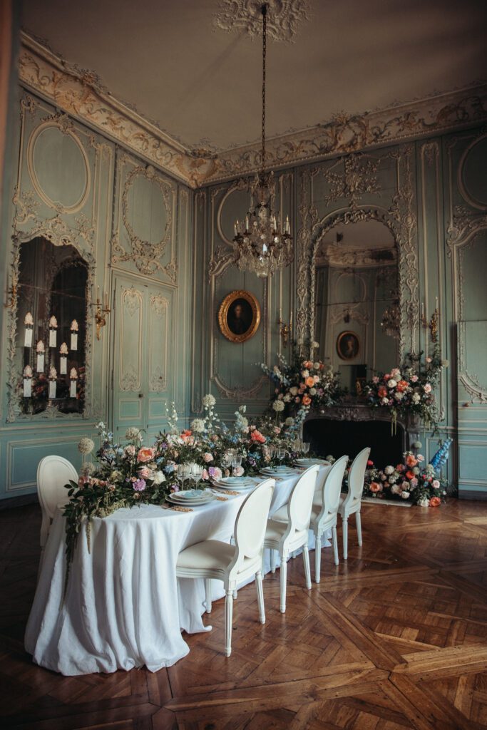 An elegant blue room at the wedding venue chateau de champlatreux in France. featuring a table covered in flowers. 