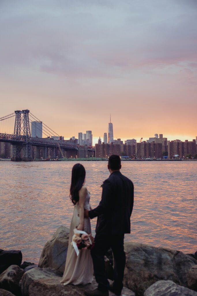 Couple embracing at sunset looking towards the New York City skyline after. 