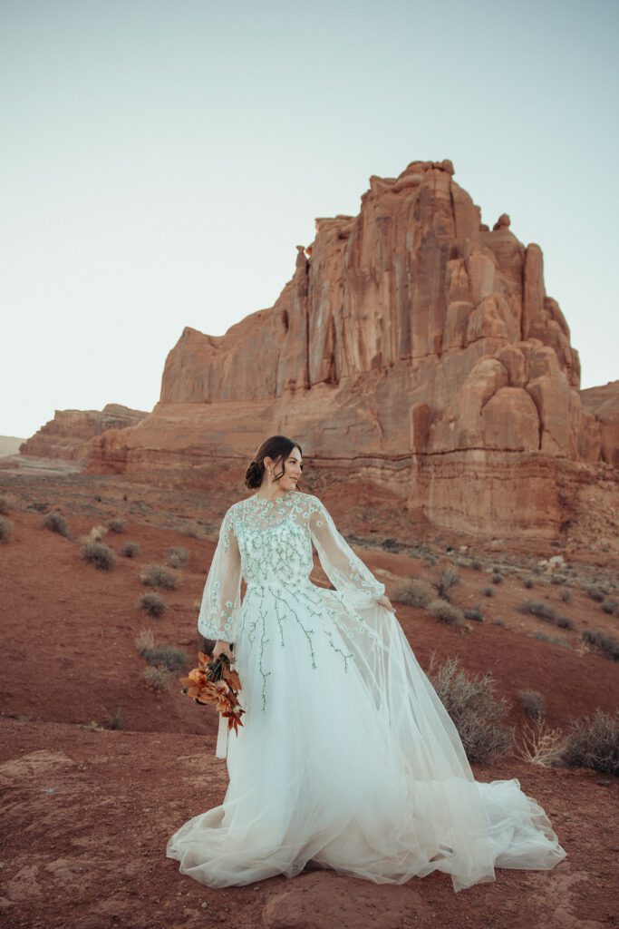 Columbus, Ohio wedding photographer traveling to Moab. Bride standing holding bouquet among the natural beauty of Moab. 