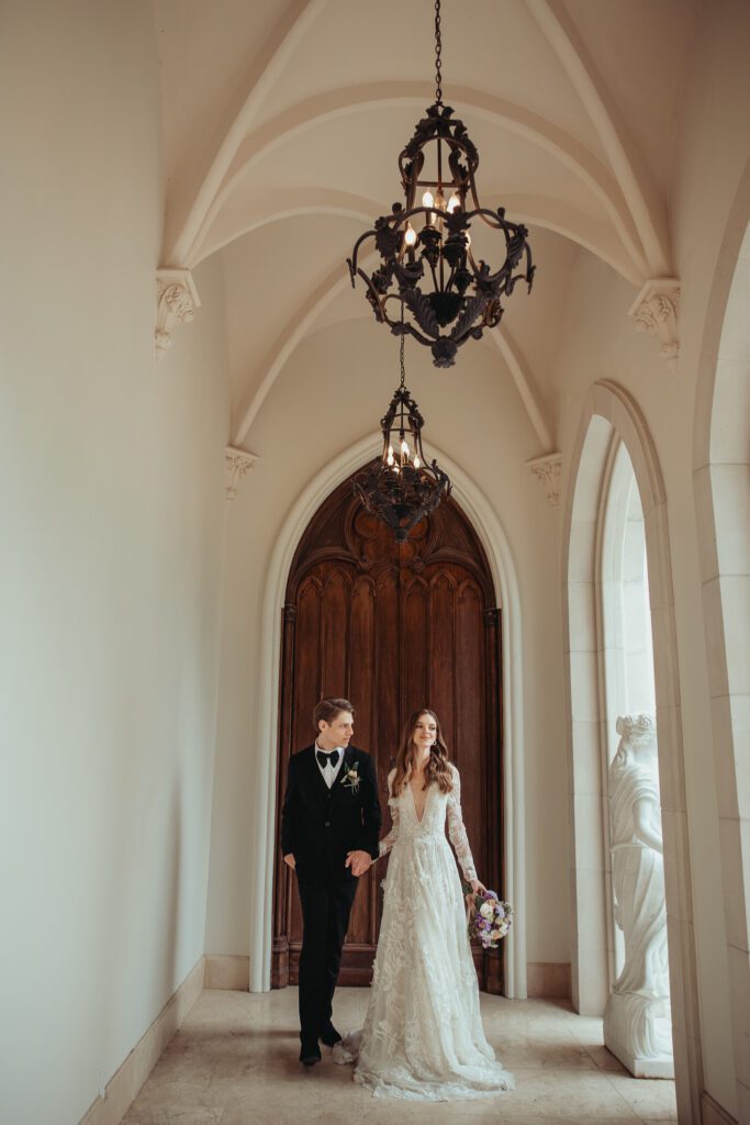 Couple holding hands and walking away from a large, ornate wooden door at Chateau Nouvelle in Houston, Texas