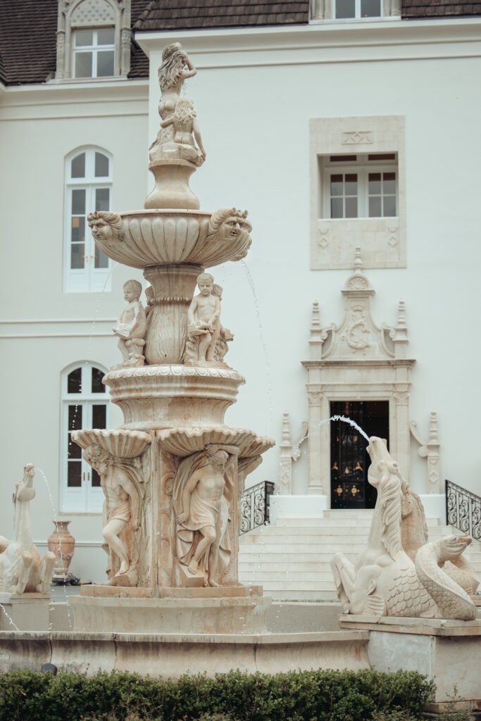 An ornate stone fountain in front of Chateau Nouvelle