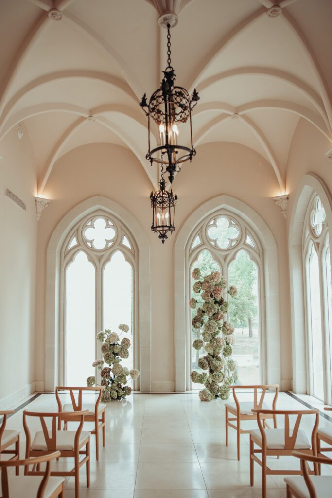 Inside of Chateau Nouvelle, decorated for a wedding ceremony with floral arches and chairs.
