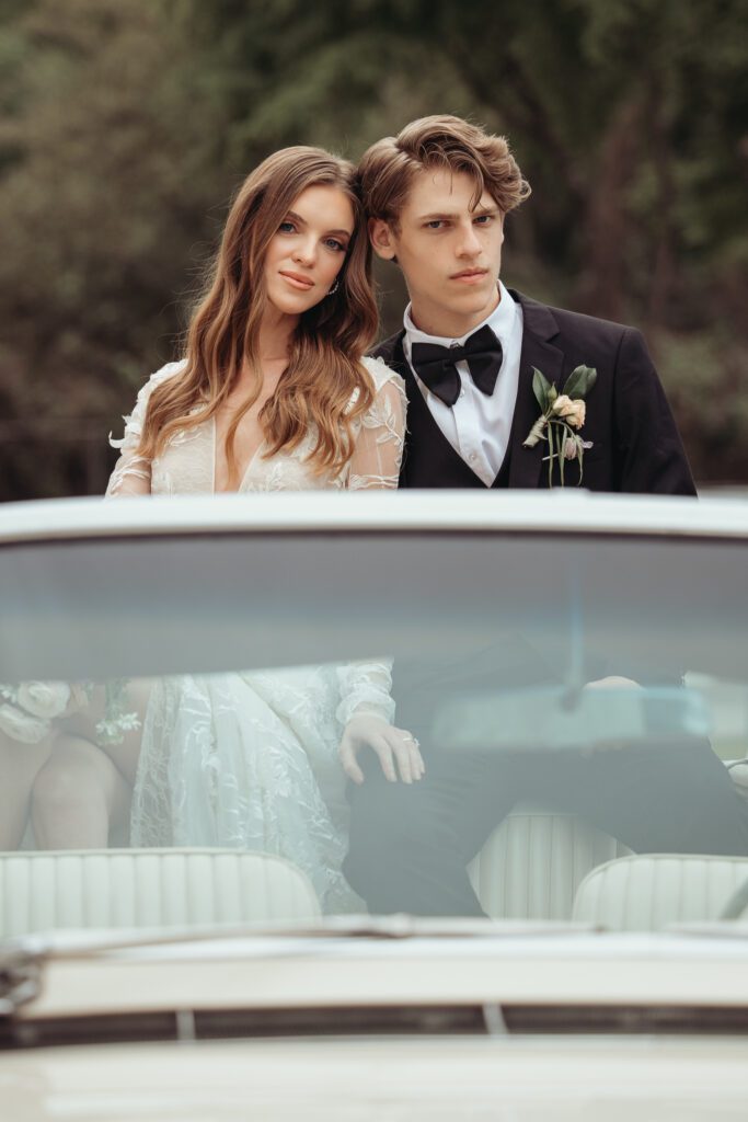 Bride and groom sitting in a vintage car outside of Chateau Nouvelle